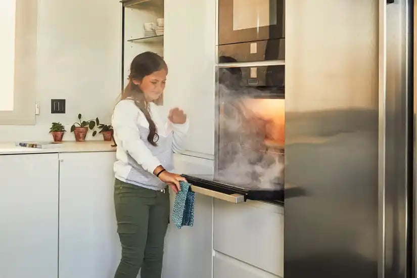 niño abriendo el horno y teniendo en mente la prevención de incendios en el hogar